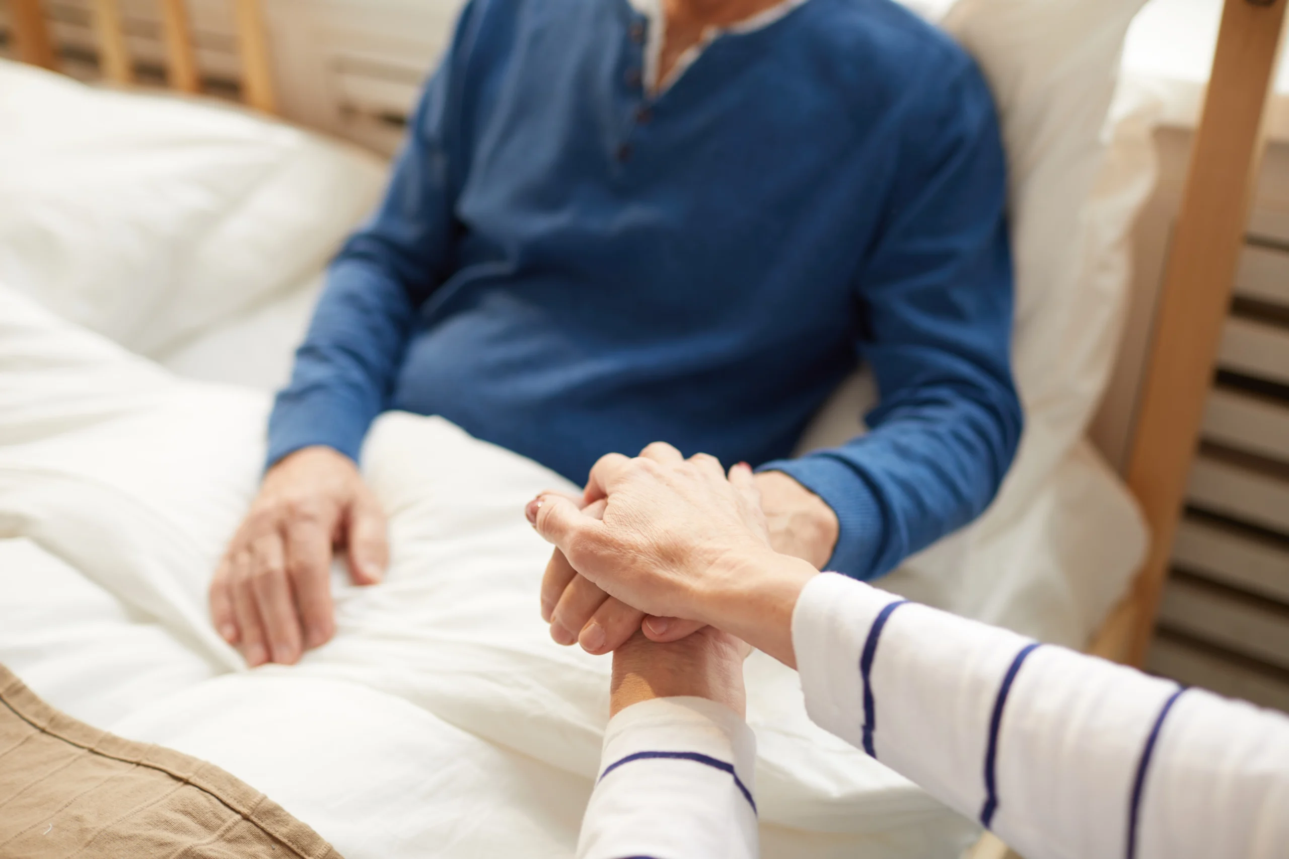 couple holding hands in a hospice room