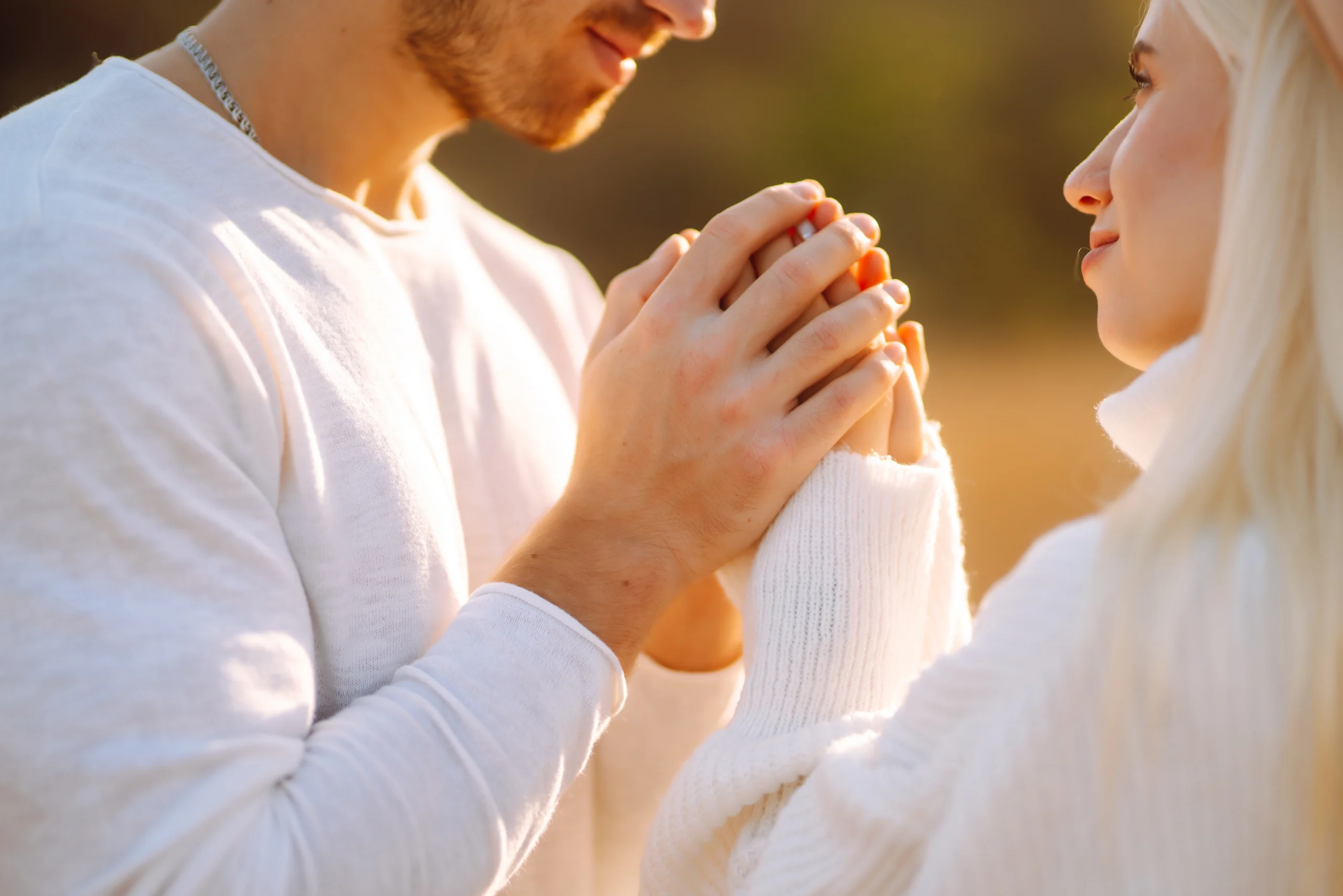 couple holding hands praying during sunset