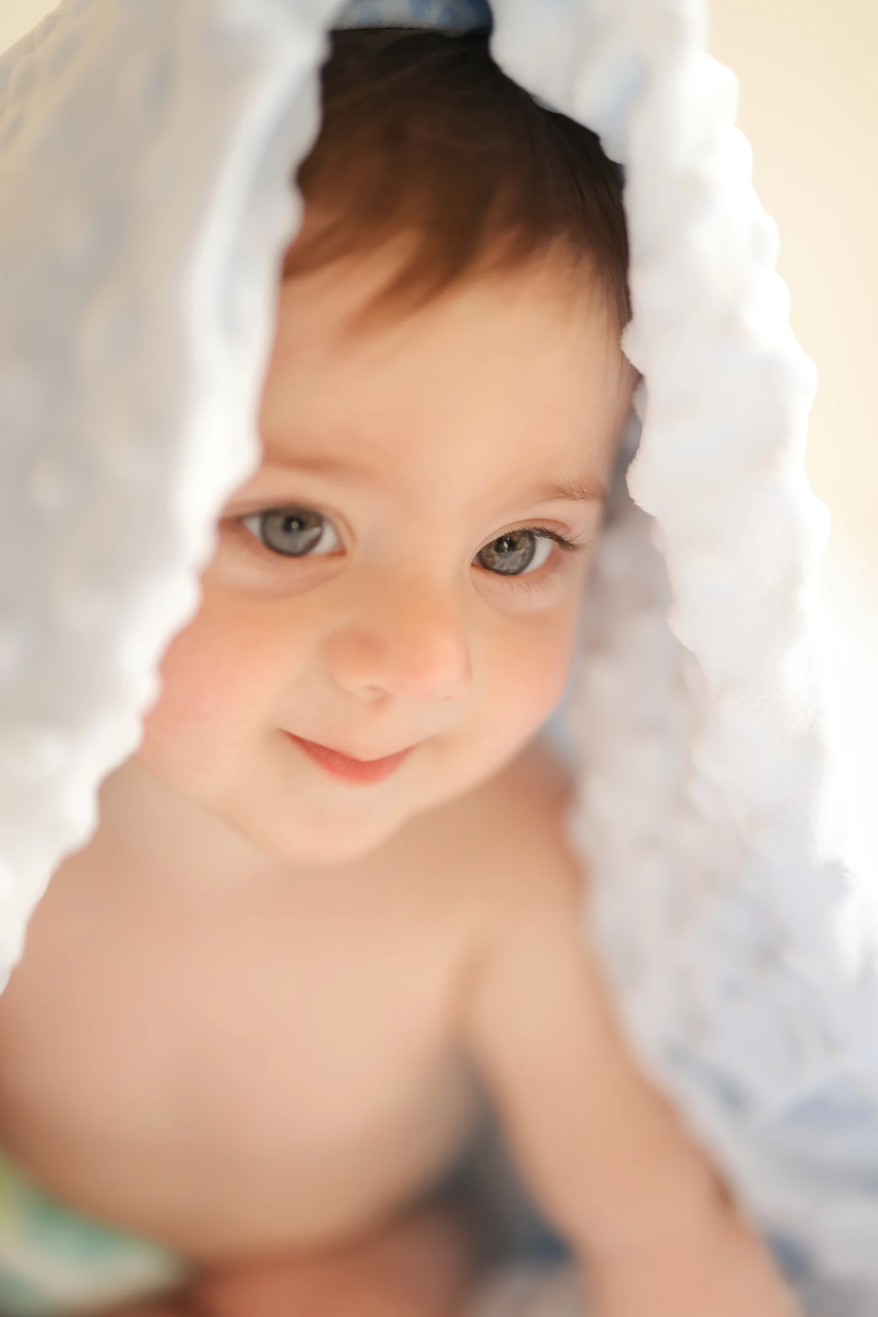 baby with blanket over their head smiling