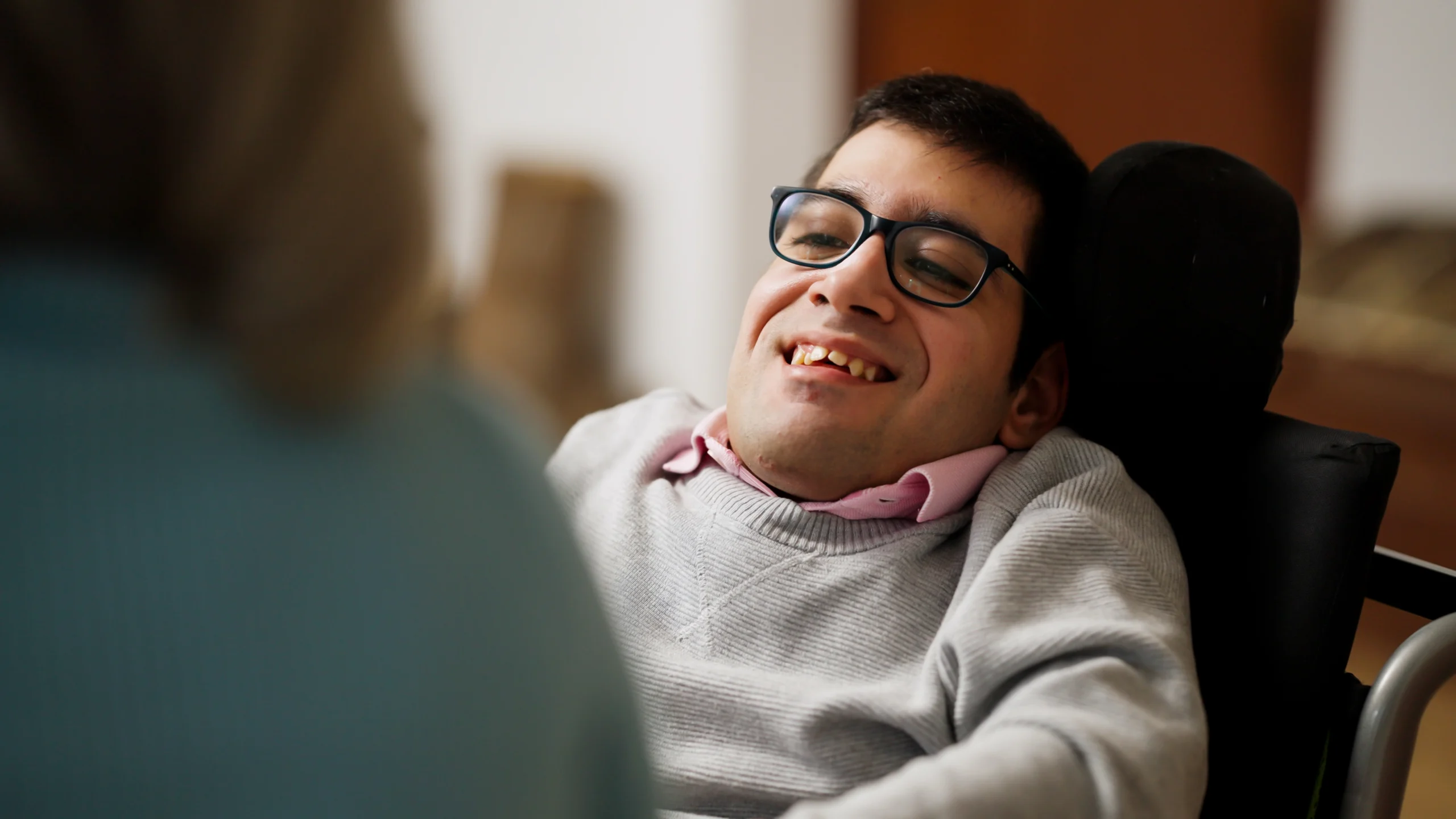 man in a wheelchair smiling and wearing glasses