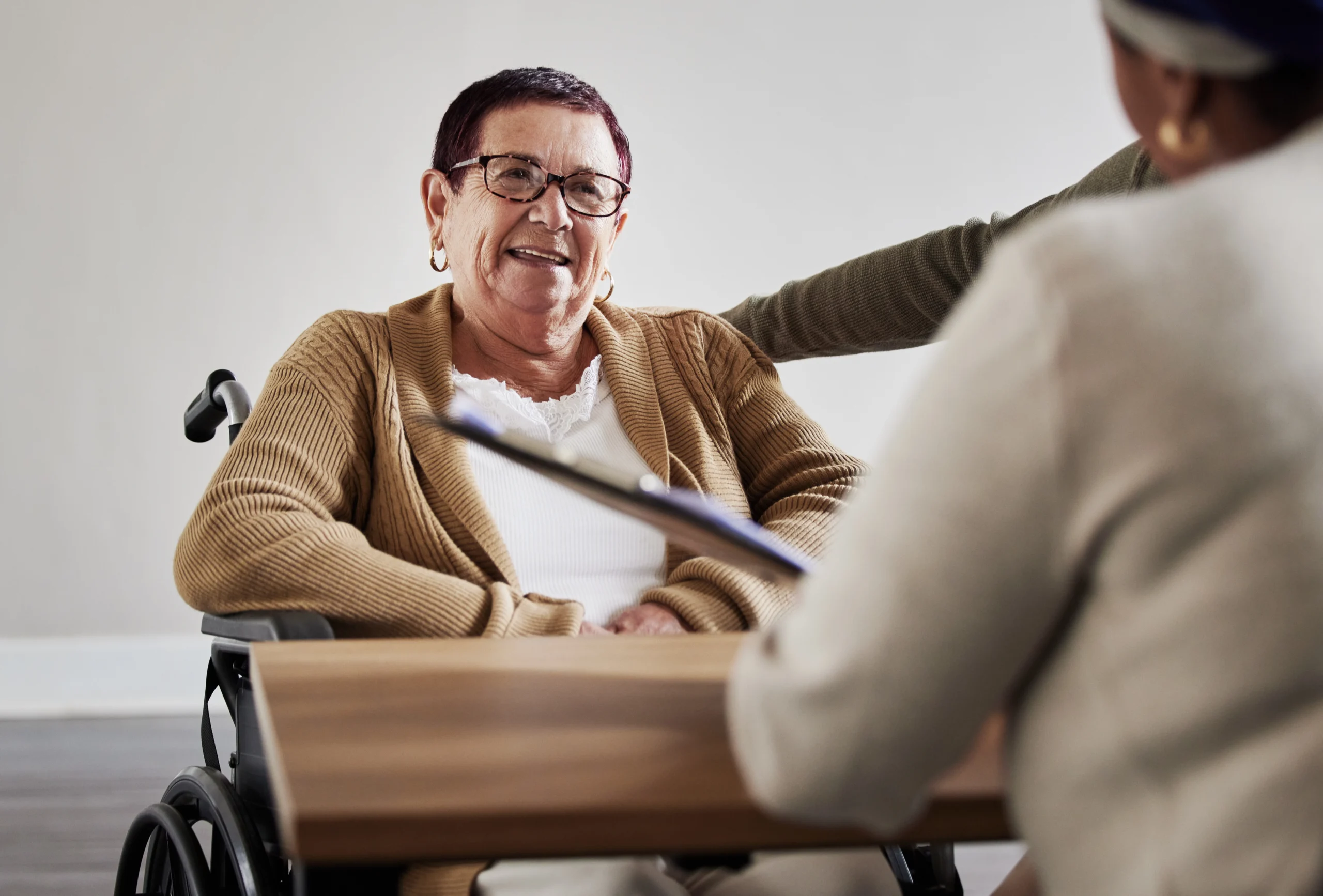 senior woman smiling at a desk talking with a business woman