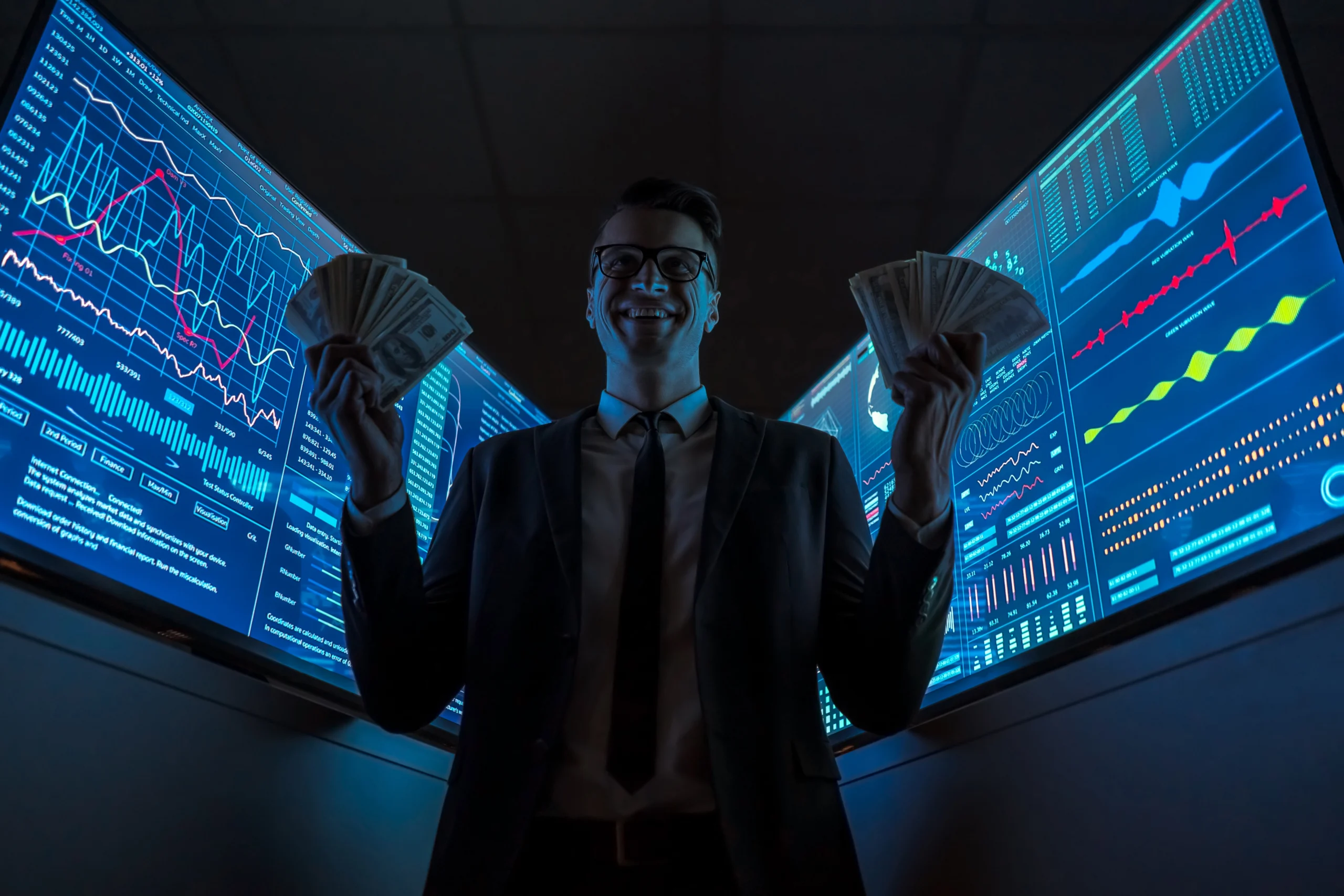 businessman holding cash with computer screens behind him
