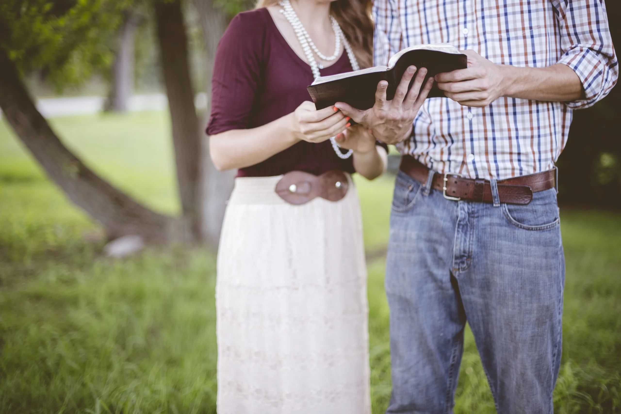 man and woman reading a Bible together outside
