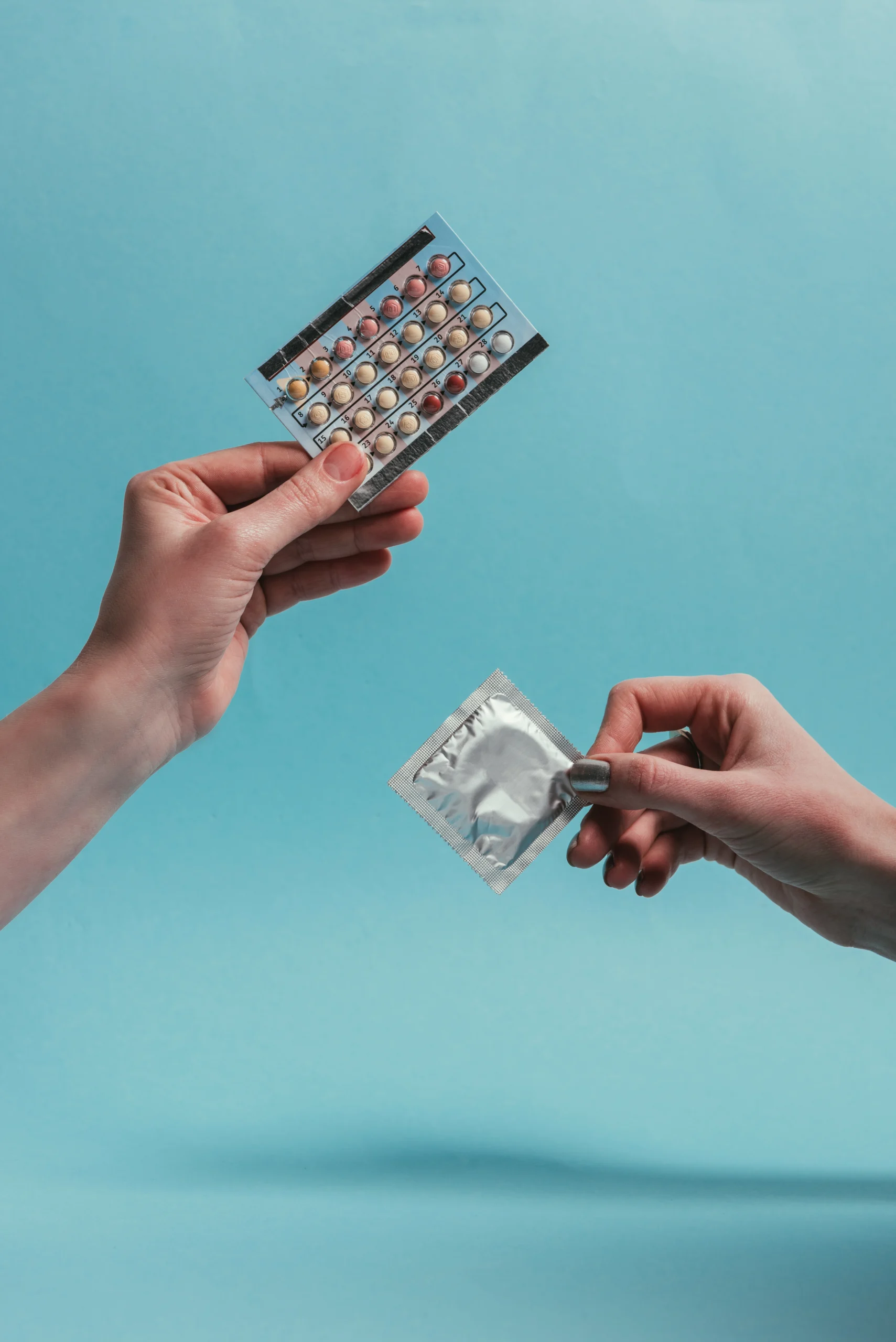 man holding birth control and woman holding a condom