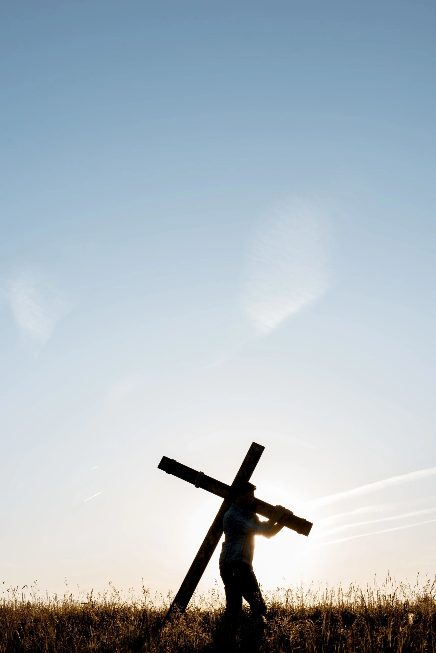 man carrying a cross during sunset