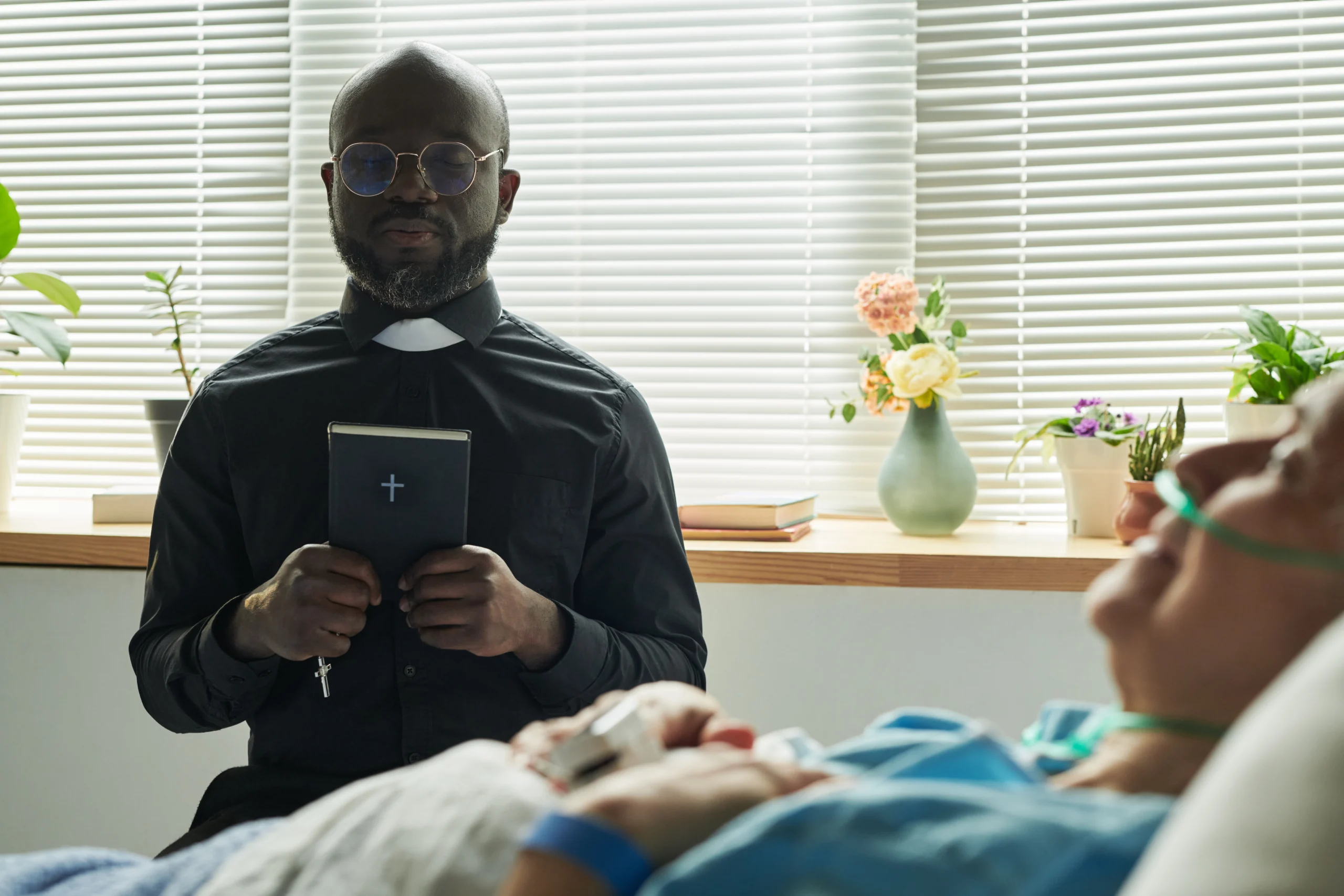 pastor praying over a sick woman in the hospital